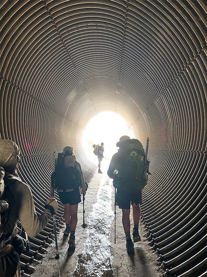 Vaeltajat kävelemässä tunnelissa.