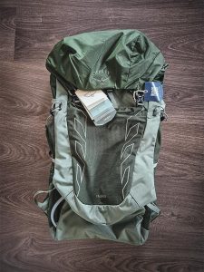 Osprey Talon 33 -reppu kuvattuna ylhäältäpäin tuotelappujen kanssa puulattialla.