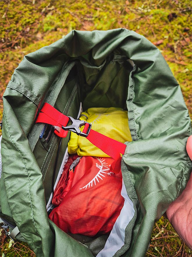 Osprey Talon 33 -repun sisäpuoli, jossa retkivarusteita ja kirkkaan punainen kompressioremmi.