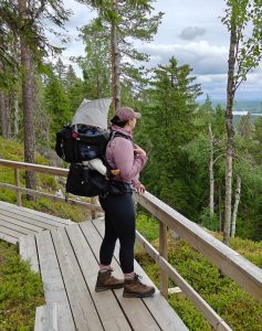 Aikuinen kantaa lasta lastenkantorinkassa näköalatasanteella havumetsässä.