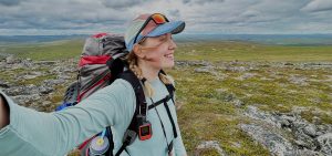 Nainen ottaa selfiekuvan taustalla Muotkatunturien tasaista maisemaa.