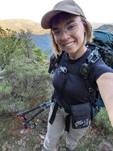 Retkeilijä ottaa selfien suuri reppu selässään vuoristoisella metsäpolulla.