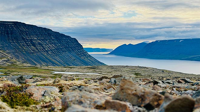 islannin länsivuonojen jyrkät vuoret ja vuono avautuvat kivikkoisen ylängön takana.