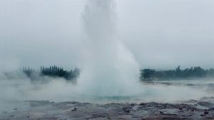 geysir purkautuu korkealle ilmaan höyryävän kuuman lähteen keskeltä islannissa.