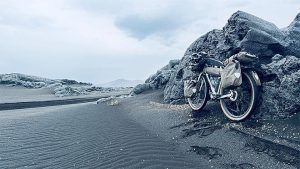 lastattu bikepacking-pyörä mustalla hiekalla laavakivien vieressä islannin ylängöllä.