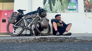 pyöräilijä istuu lastatun bikepacking-pyöränsä vieressä tauolla islannissa.